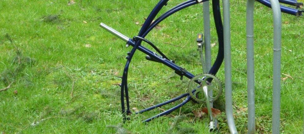 Damaged bicycle frame and parts discarded in grass