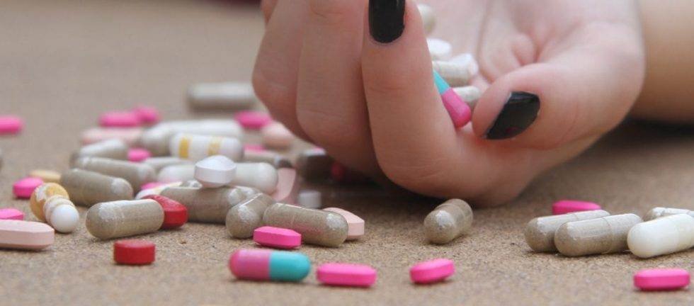 Close-up of hand scattering pills; possible drug overdose.