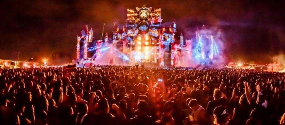 Massive crowd at an outdoor music festival, enjoying a vibrant stage show.