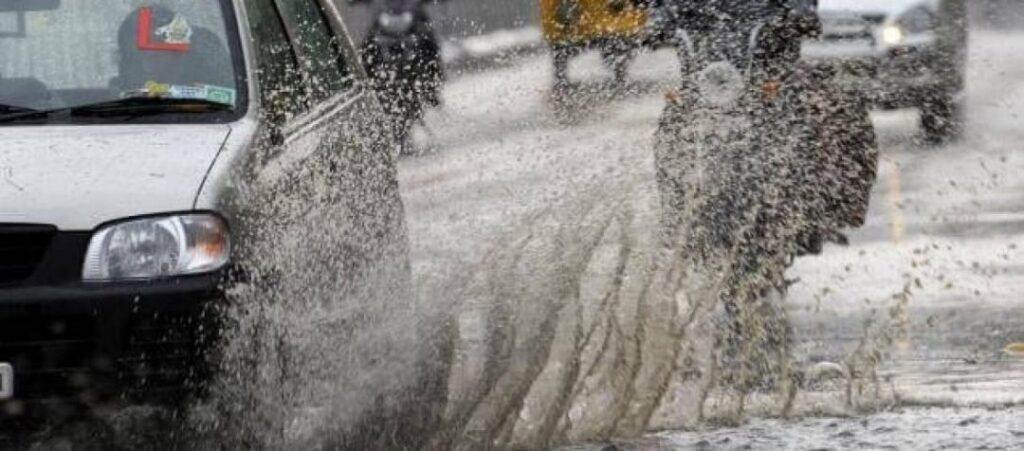 Car splashing through a deep puddle on a rainy road.