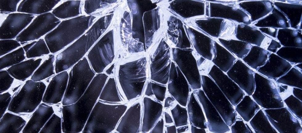 Close-up view of a cracked glass screen, showing a spiderweb pattern of fractures.