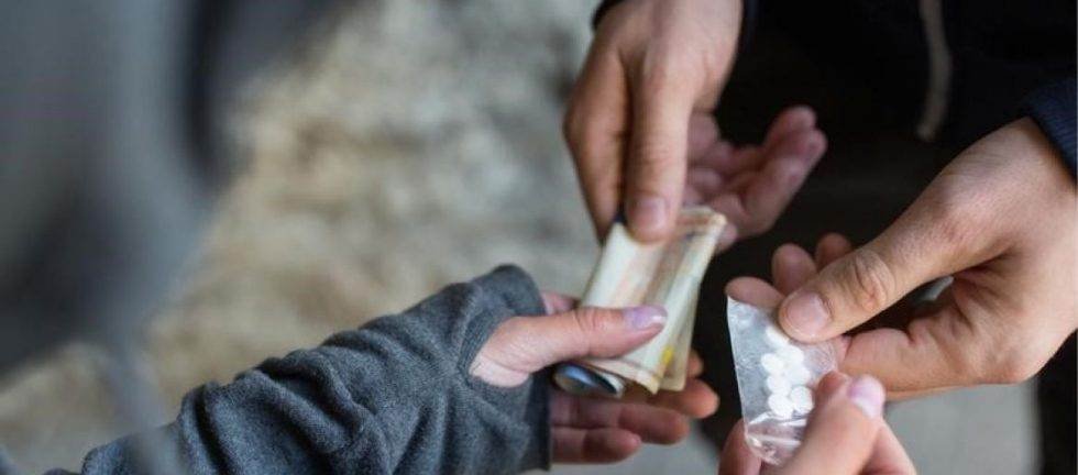 Close-up of a drug deal: hands exchanging money and pills.