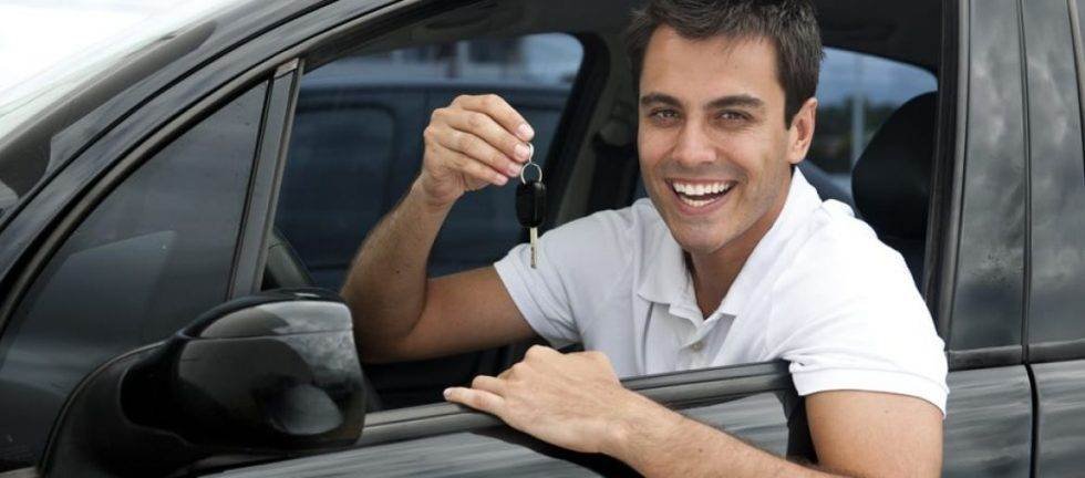 Happy man holding new car keys. New car purchase.