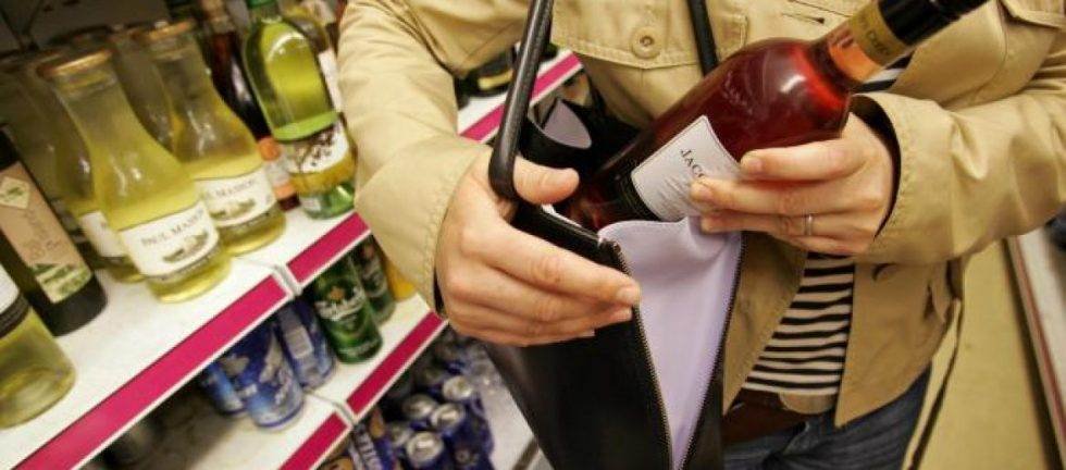 Woman concealing bottle of wine in purse.