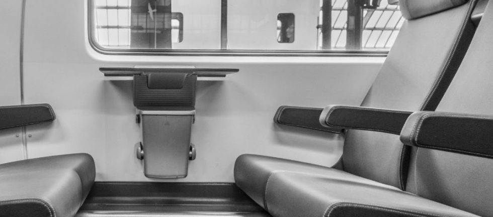 Modern train seating with fold-down table. Comfortable passenger chairs and armrests.