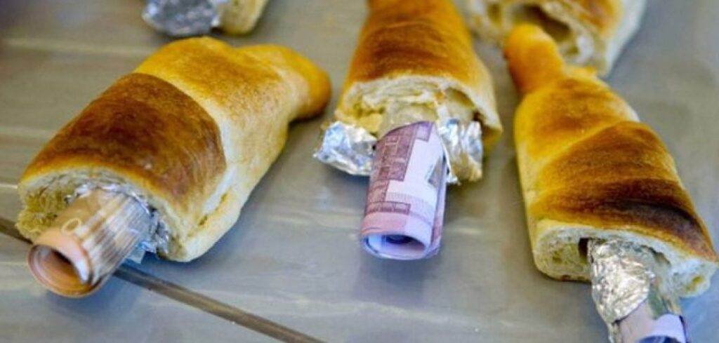 Several baked bread rolls with euro banknotes hidden inside, wrapped in foil.