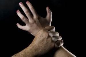 A hand gripping another wrist forcefully, illustrating domestic violence.