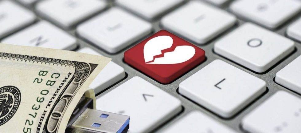 Broken heart on keyboard with USB drive and money; online heartbreak, financial loss
