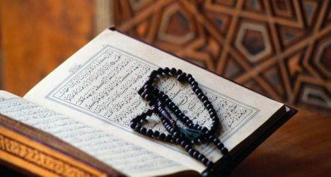 Open Quran with prayer beads; Islamic text visible.