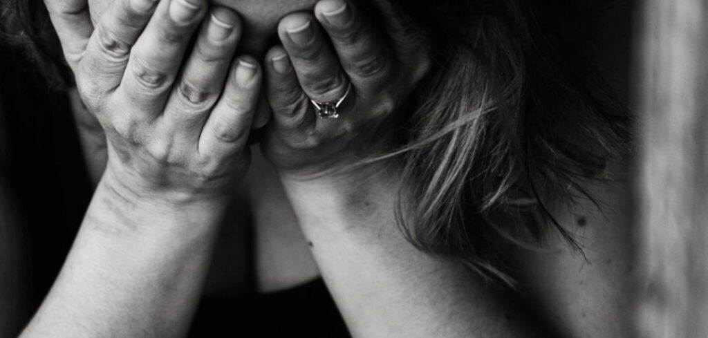 Woman with hands covering her face, appearing distressed.
