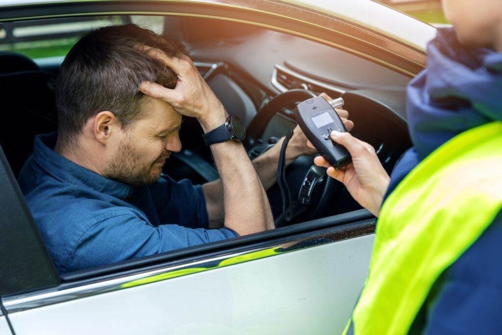 Police officer administering a roadside breath test to a stressed driver suspected of drink driving in NSW.