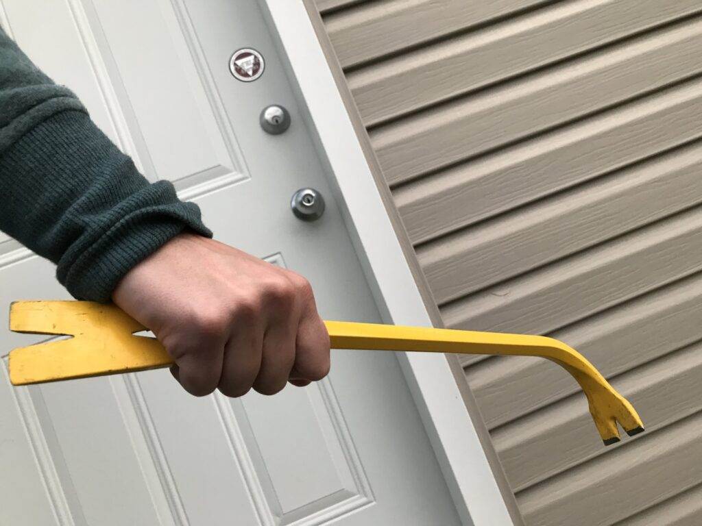Person holding a crowbar near a door; break and enter in NSW