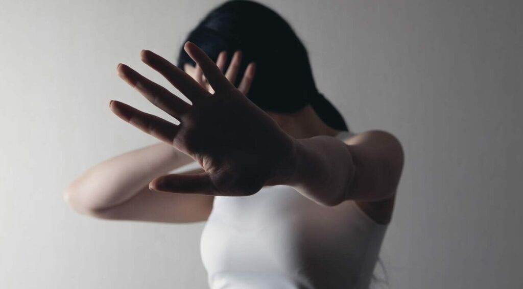 Woman shielding her face, representing sexual assault.