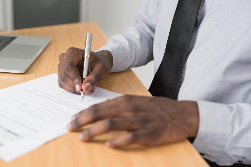 Person signing a legal document, writing an apology letter to the court for a drug offense.