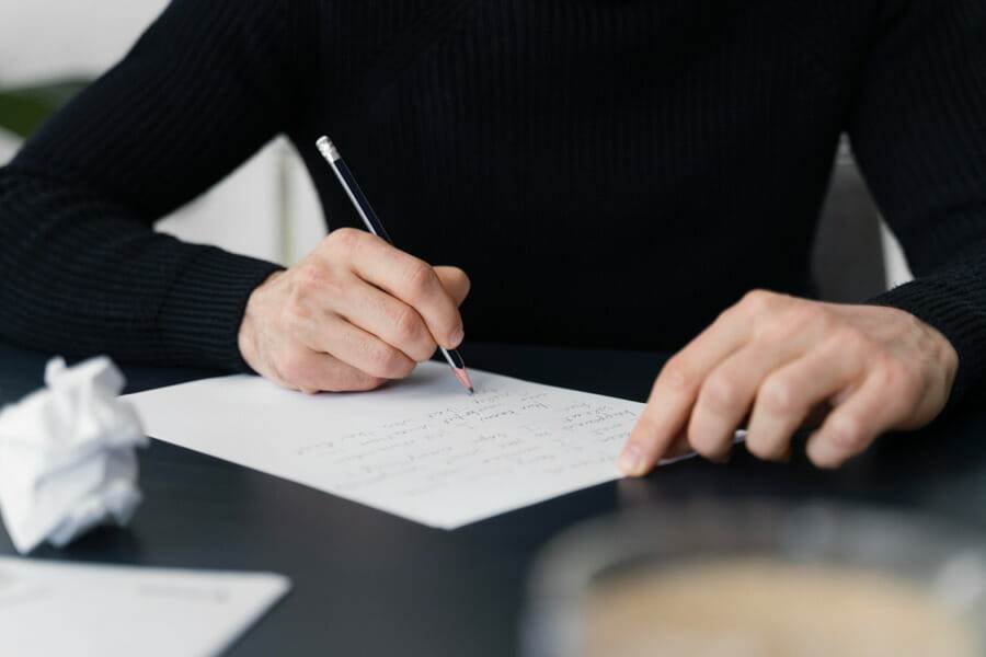Person writing a letter, possibly an apology letter for domestic violence offences.