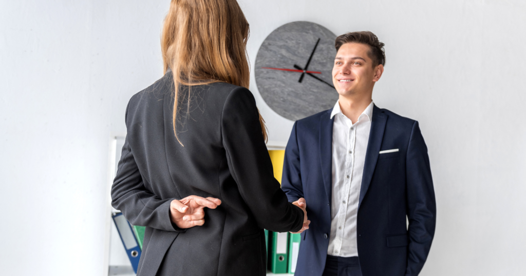 Businesswoman shaking hands, fingers crossed behind her back. Deceptive business dealings.