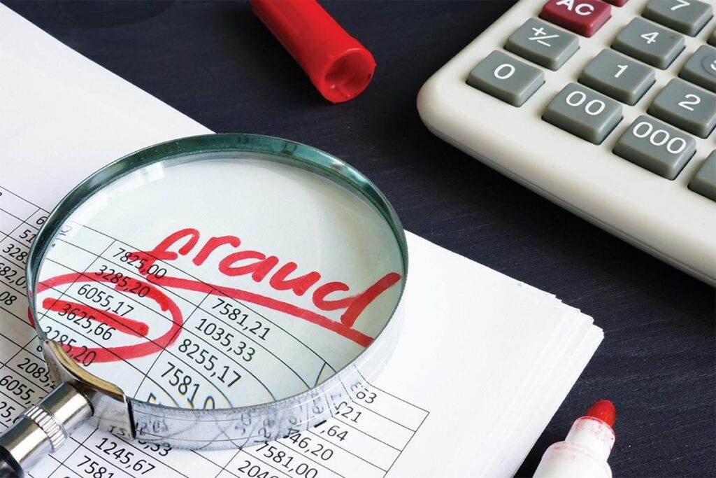 Magnifying glass over accounting documents with "fraud" circled in red. Calculator and red markers nearby.