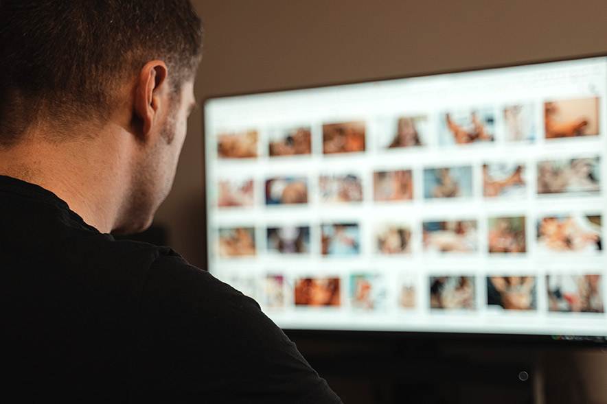 Man viewing blurred images of child exploitation on a computer screen. Understanding Child Exploitation Material Offences in NSW.