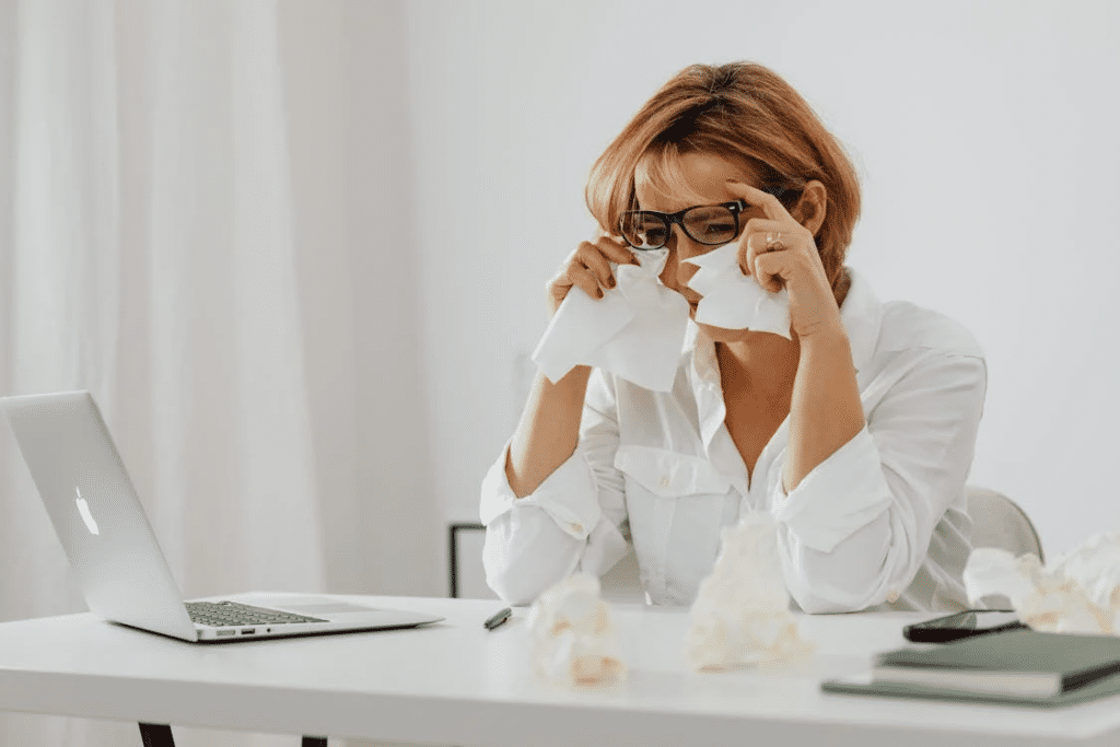 Upset woman crying at her desk, considering legal action after assault.