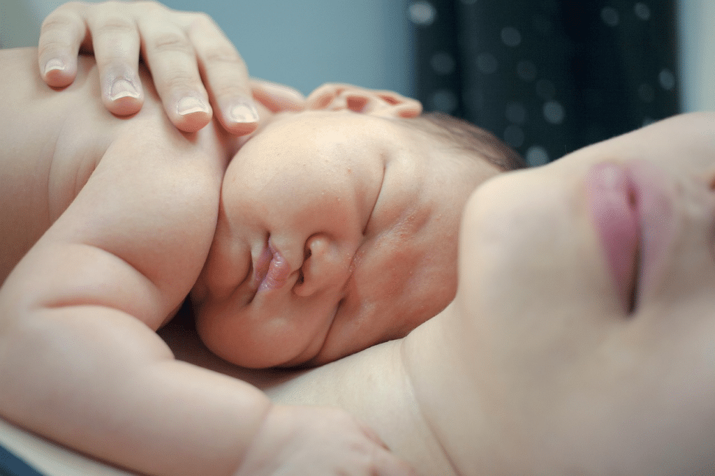 Newborn baby sleeping peacefully on its mother's chest.