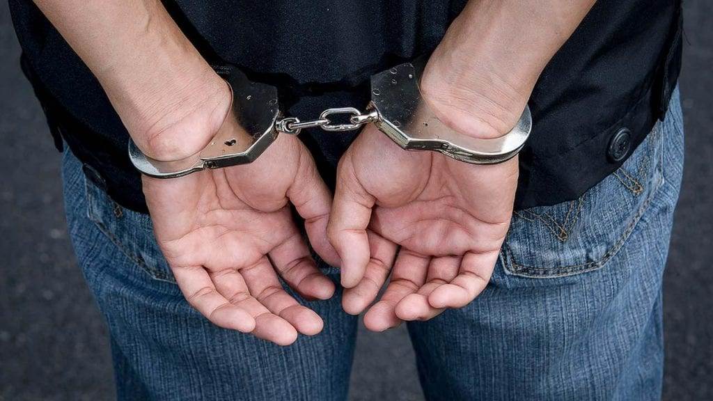 Person's hands cuffed behind their back.