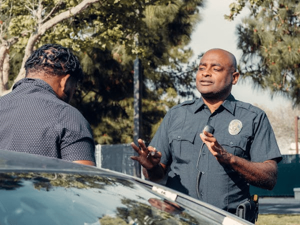 Police officer speaking to a young person near a car, highlighting NSW under 18 rights with police interaction.