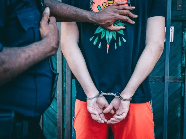 Police officer arresting a suspect, hands cuffed behind back. Resisting arrest.