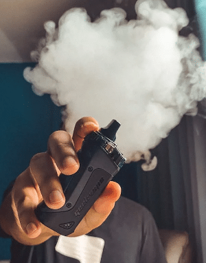 Person holding a vape with smoke. Focus on NSW vaping laws highlights regulatory impact on vaping devices and usage.