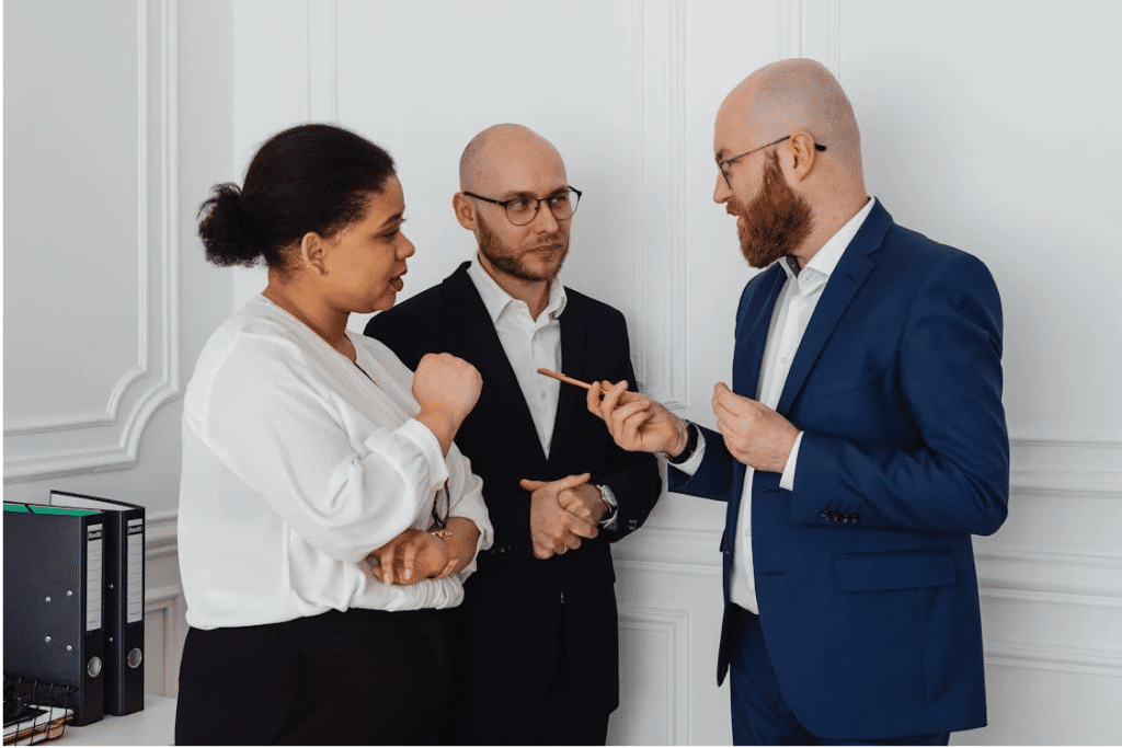 Three professionals in a discussion, possibly about ICAC policies, stand in a white office setting.