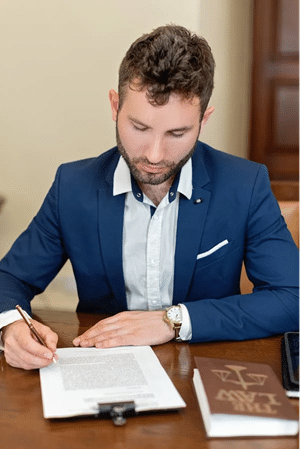 Man in a suit signing a document at a desk, focusing on NSW identity information laws and protection.