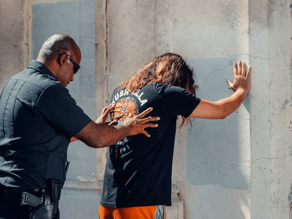 Police officer conducts a frisk search on a person against a wall, illustrating criminal check procedures in NSW.