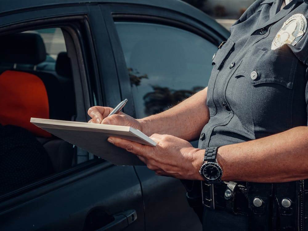 Police officer writing a ticket by a car, illustrating fines and monetary penalties in NSW criminal law.