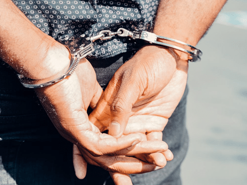 Person in handcuffs representing consequences of breaching an Apprehended Violence Order (AVO) in NSW; penalties and defenses.