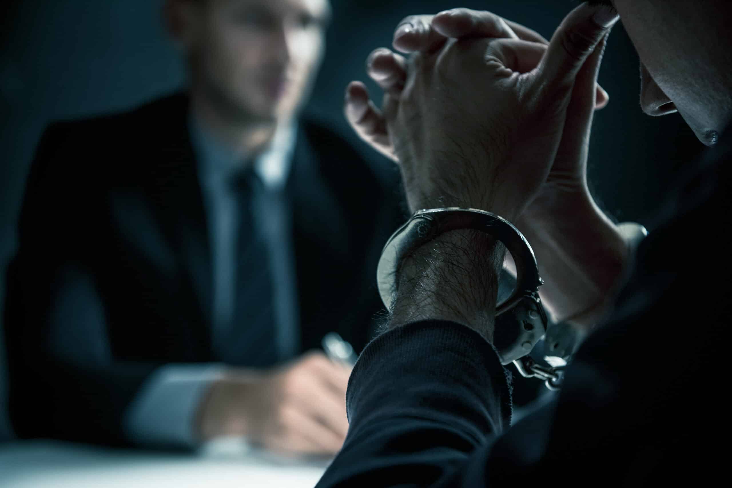 Handcuffed person in a serious discussion, illustrating NSW's Defence of Extreme Provocation: Murder to Manslaughter Guide.