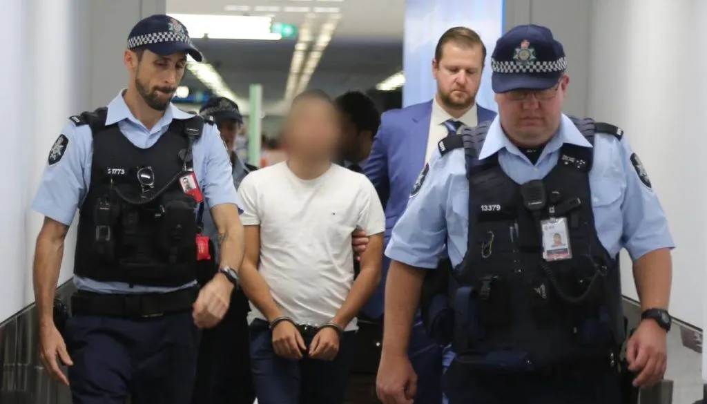 Police officers arresting a handcuffed individual in a corridor in NSW, illustrating legal arrest powers in New South Wales.