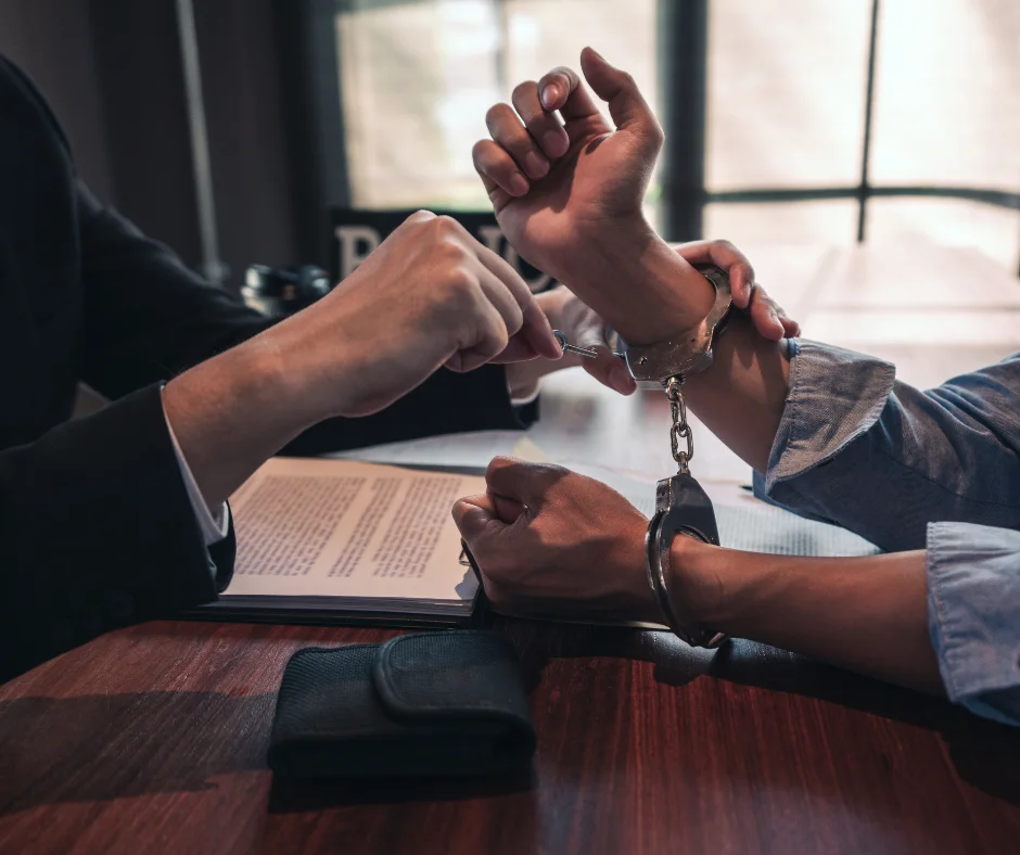 Person in handcuffs signs legal document, illustrating serious criminal charges and indictable offences in NSW guide.