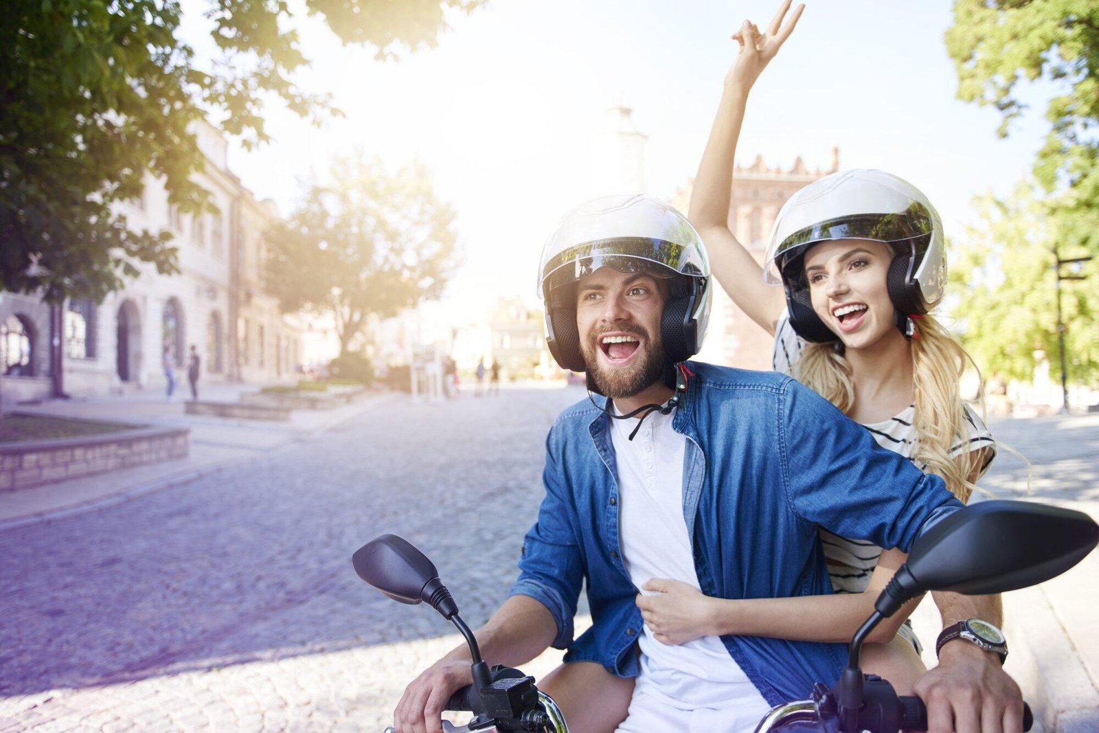 Happy couple on a scooter, wearing helmets, enjoying a ride.