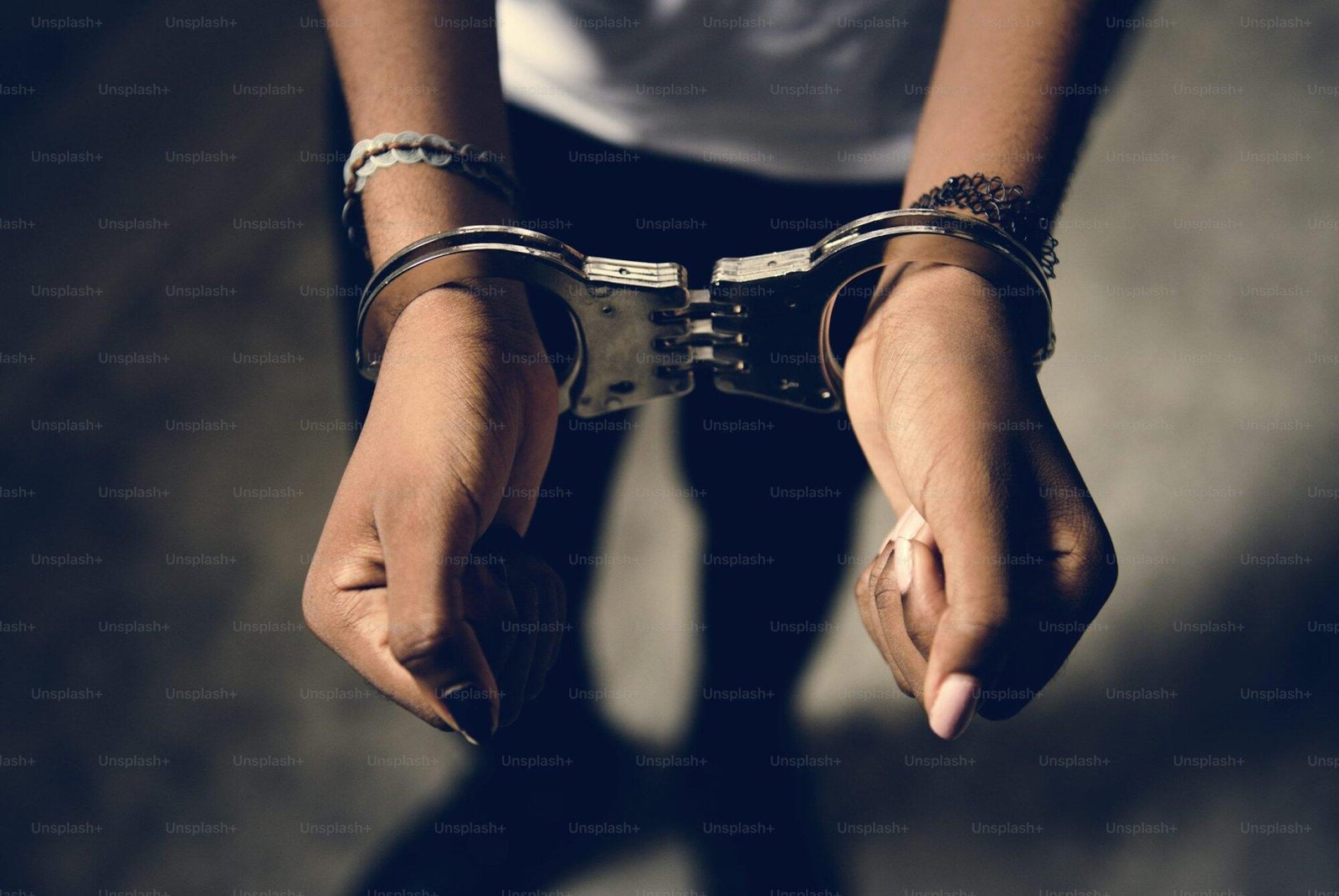 Hands in metal handcuffs against a dark background, exploring legality of handcuffs in NSW.