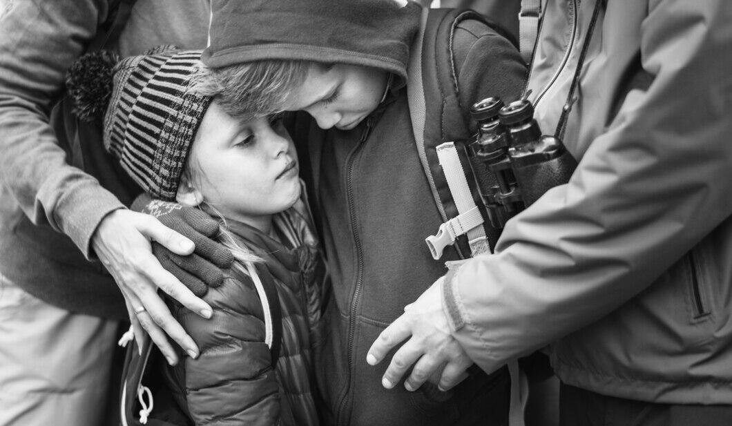 Children embraced by adults outdoors, symbolizing protection. Are sex offender registry and child protection register the same?