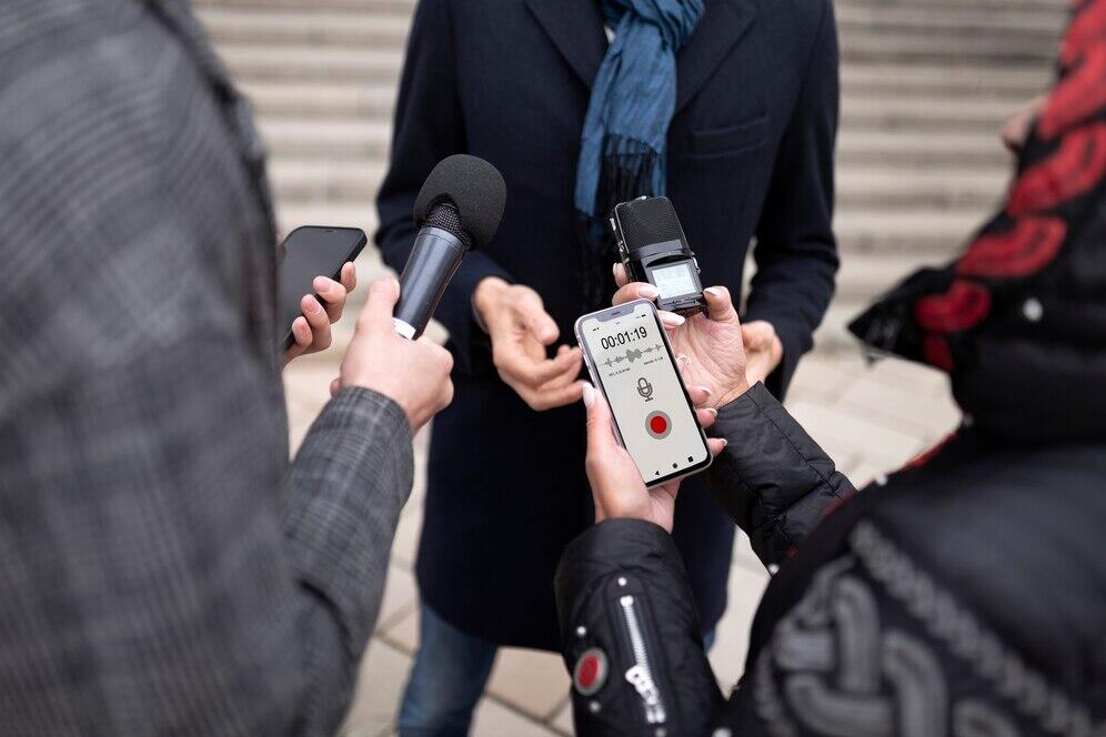 Three people holding phones and microphones, discussing recording consent laws.