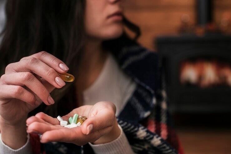 Close-up of a woman's hands holding various pills and capsules.