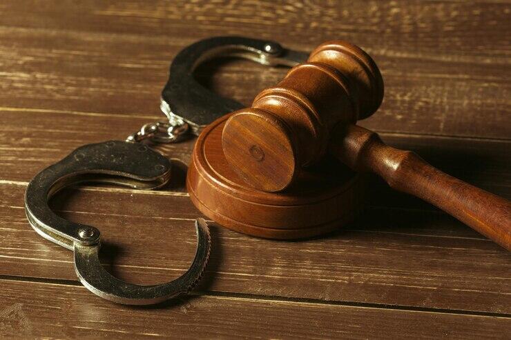 Wooden gavel and handcuffs on a wooden surface. Symbol of justice and criminal law.