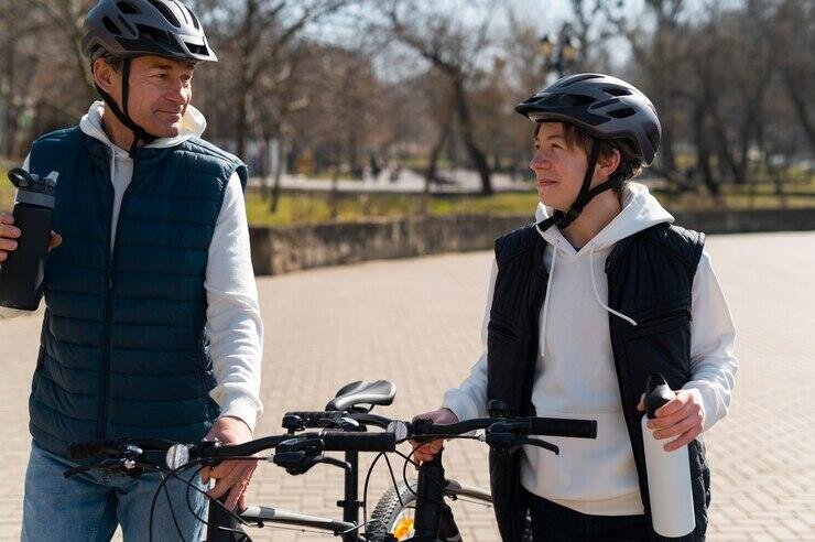 Father and son wearing helmets, holding e-bikes in NSW.