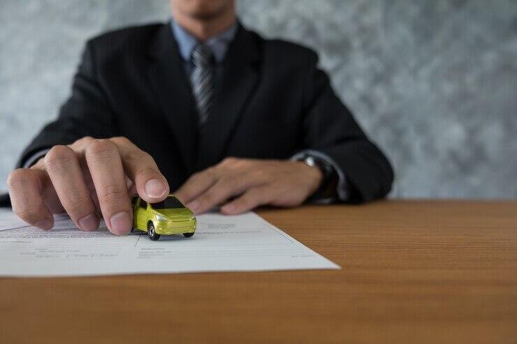 Businessman's hand placing toy car on document. Auto loan concept.