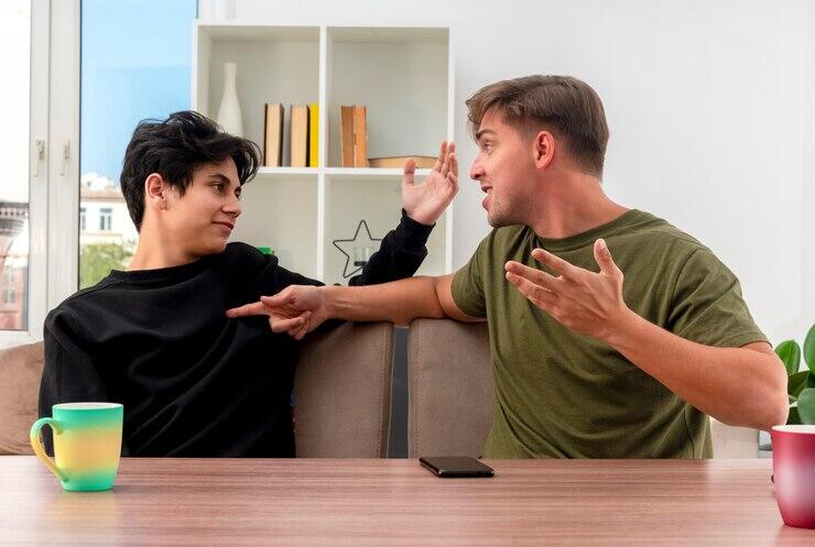 Two men arguing, one gesturing emphatically. Dispute, conflict, communication breakdown.