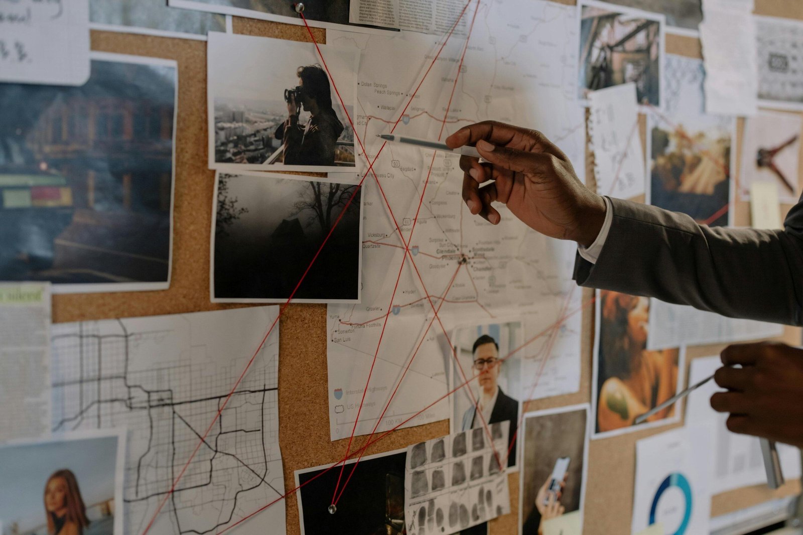 Detective reviewing evidence board with map, photos, and red string connections, investigating a case.