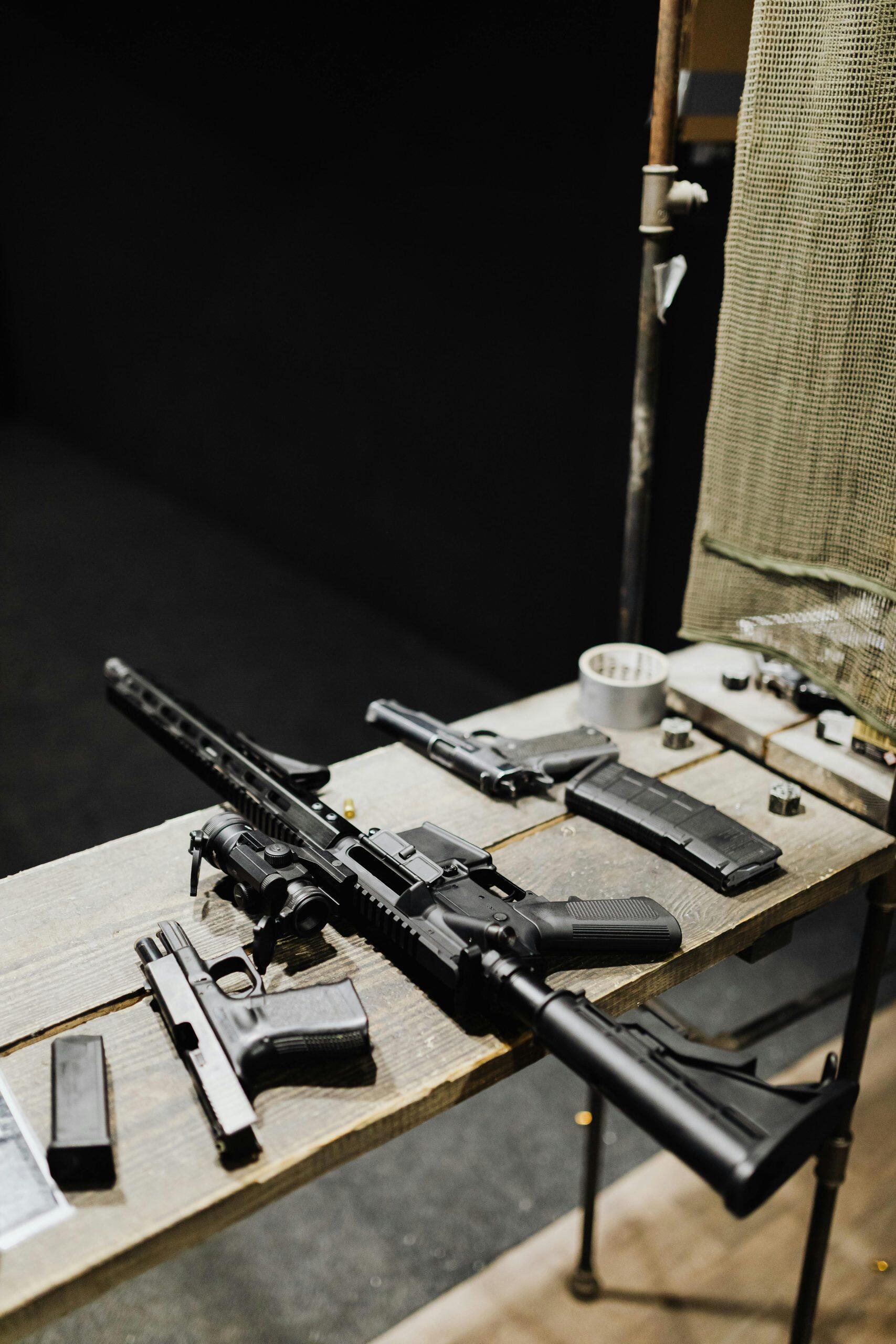 Assorted imitation firearms on a wooden table, including a rifle and handguns. NSW firearm laws.