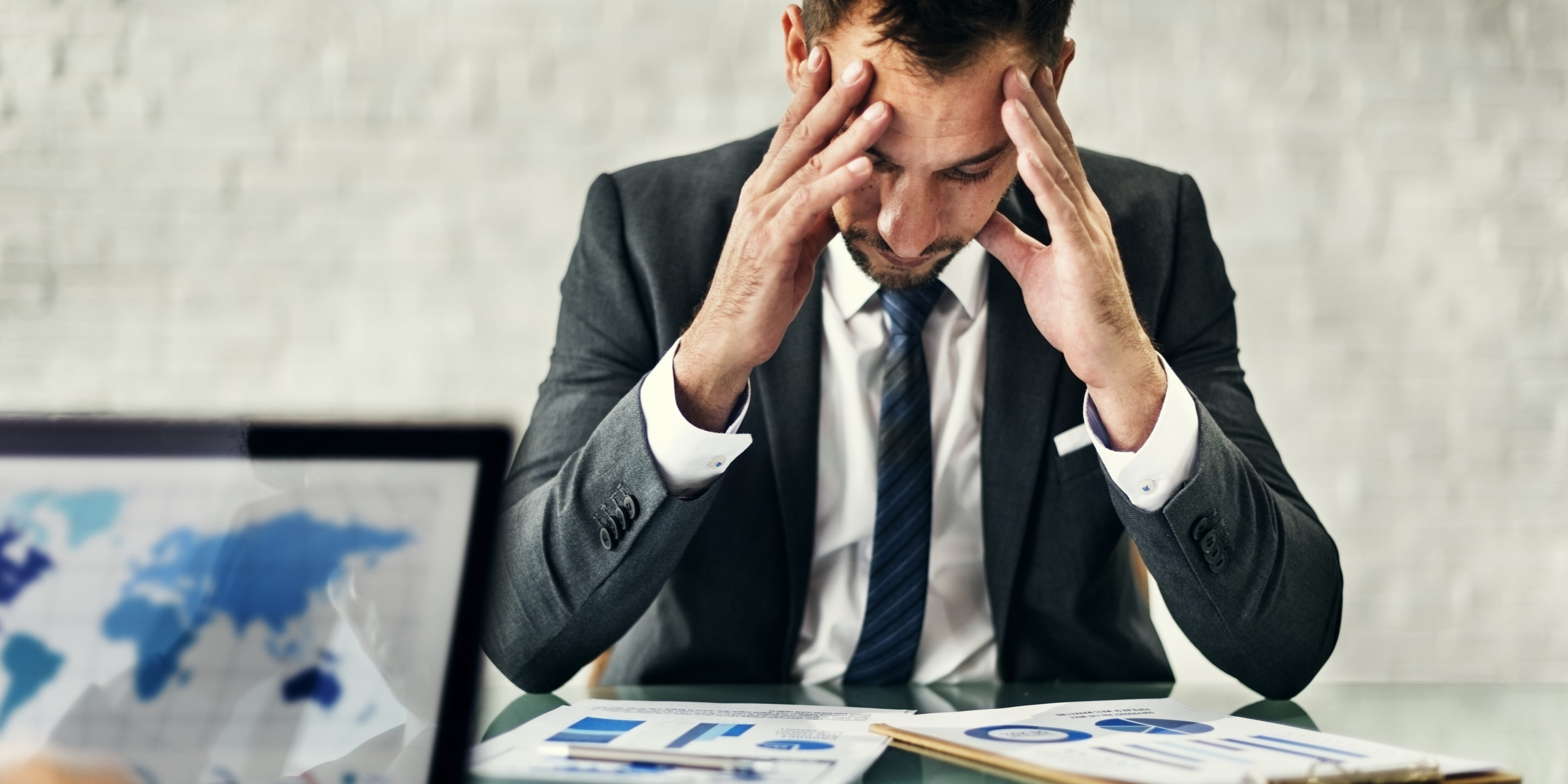 Stressed businessman reviewing financial documents at his desk.