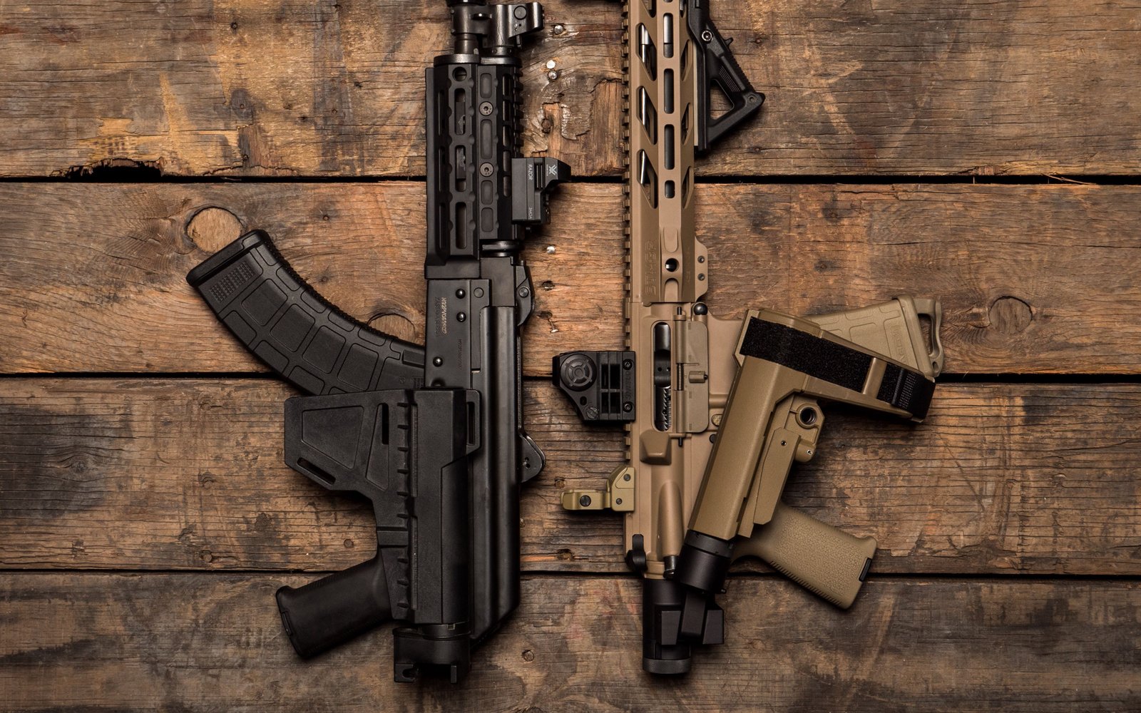 Two tactical rifles on a wooden surface
