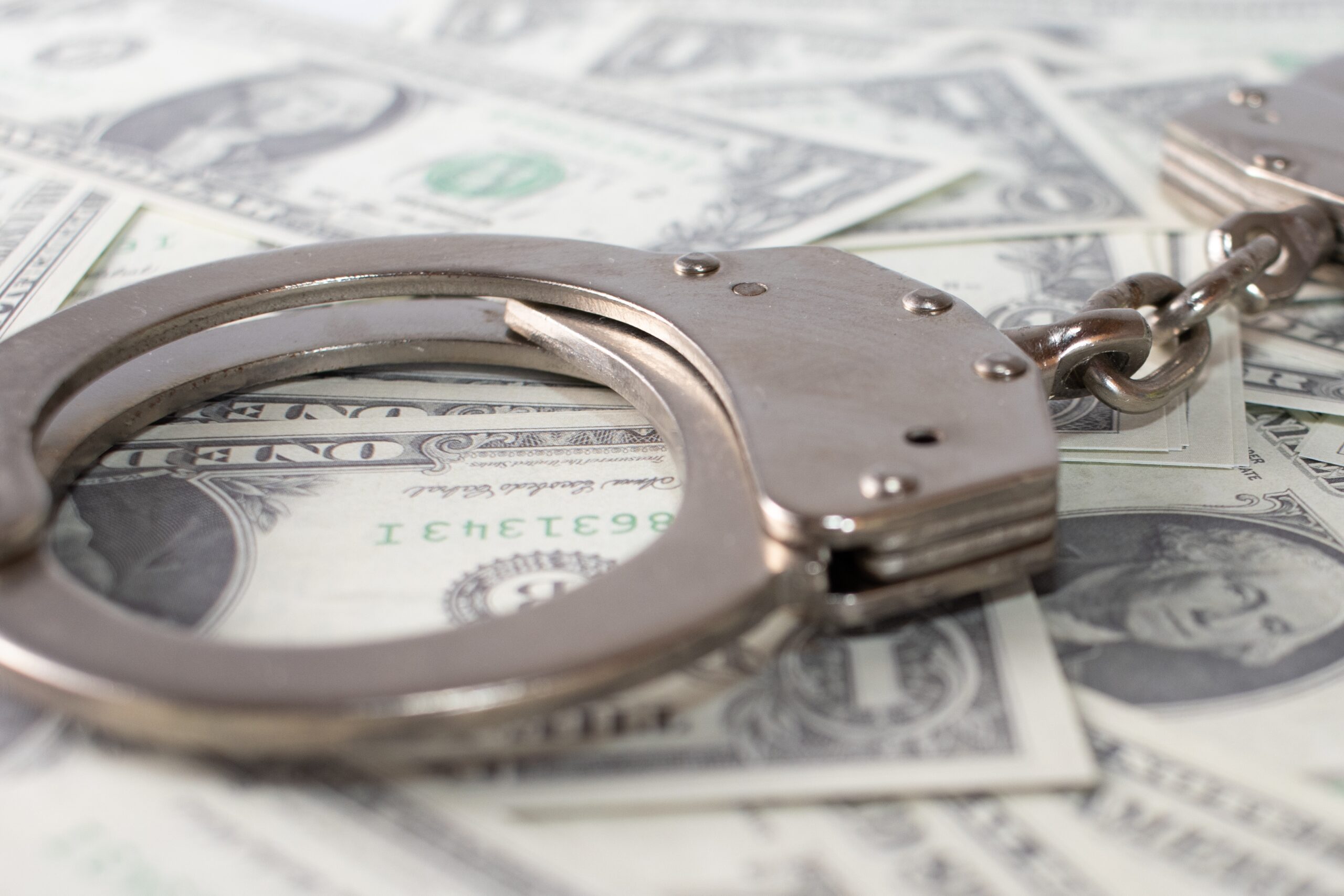Handcuffs on US dollar bills. Bribery in NSW.